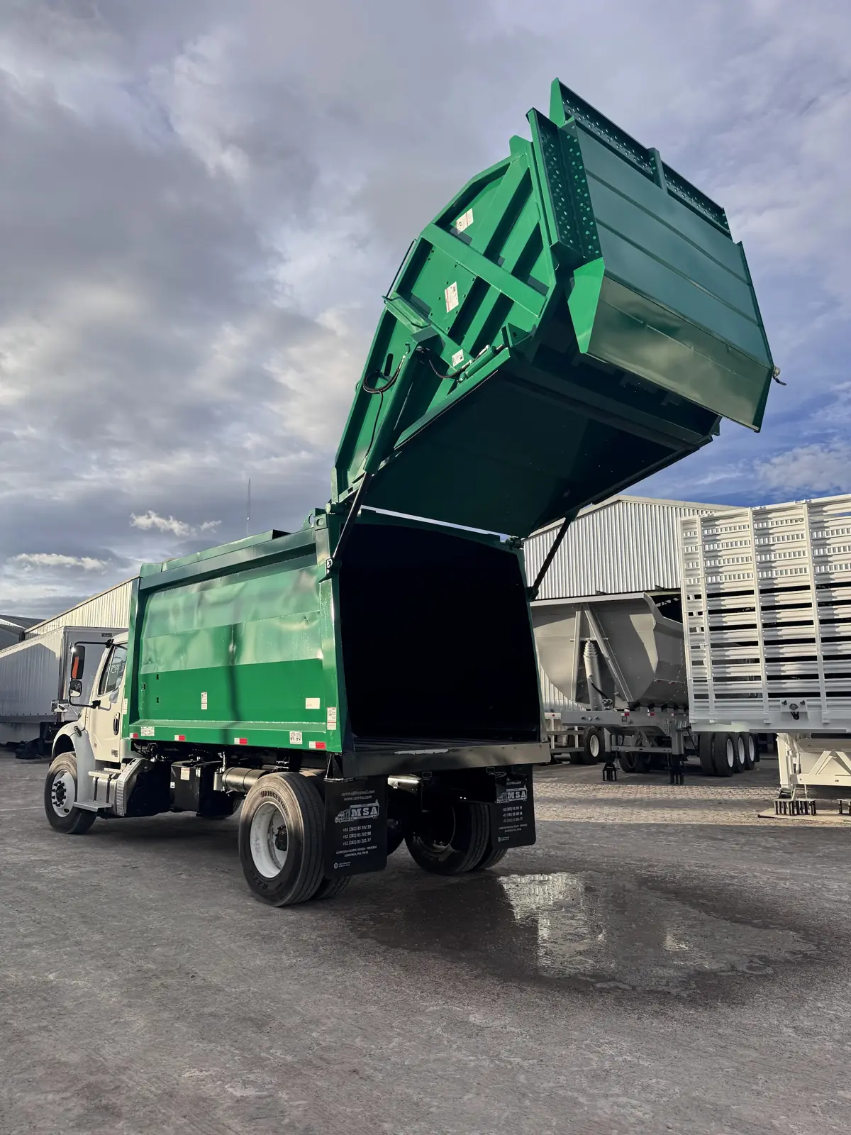 Compactador de basura MSA de carga trasera con la compuerta levantada, sobre chasis Freightliner